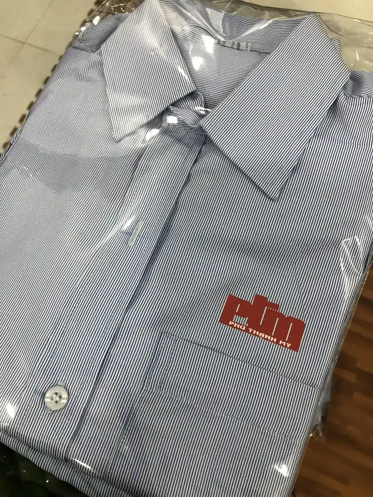Cận cảnh logo Phú Thạnh Mỹ trên áo sơ mi sọc xanh