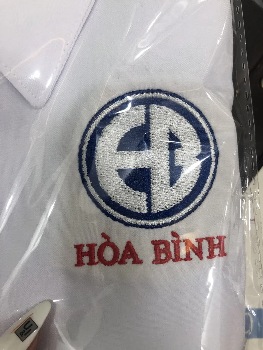 Cận cảnh logo thêu Hòa Bình trên áo sơ mi trắng
