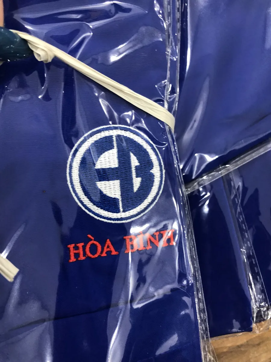Cận cảnh logo thêu Hòa Bình trên áo sơ mi xanh đậm